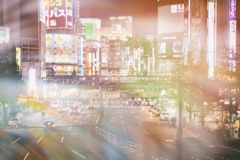 新宿大ガード越しに見る繁華街のネオン（フォトモンタージュ）の写真