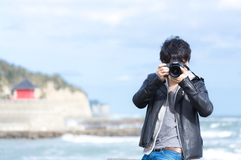 海岸でカメラを構える男性の写真