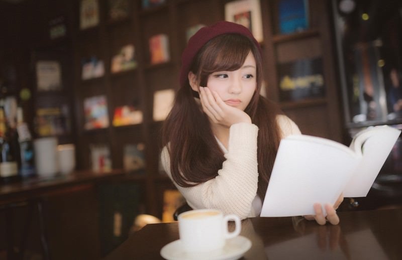 期待して購入した本にがっかりする美女の写真