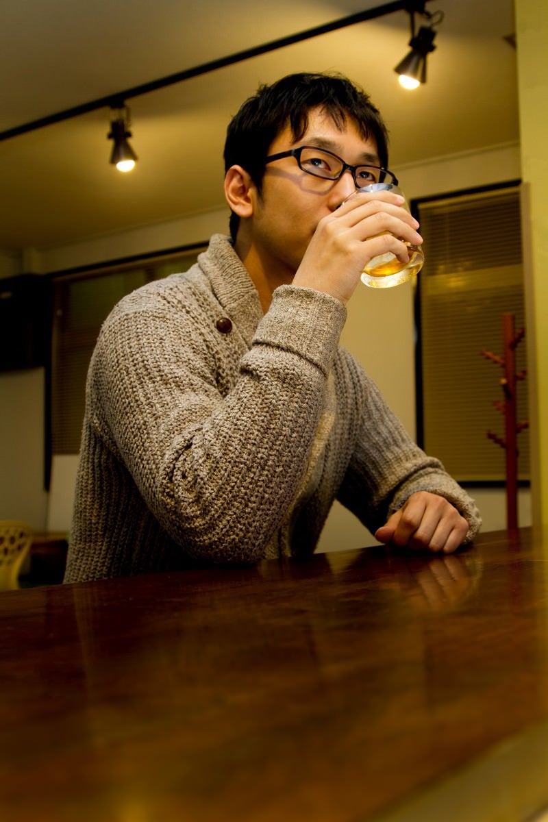 バーでグラスを持つデザイナーの写真
