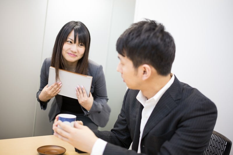 「お茶どうぞ」と意味深な笑顔で打ち合わせに茶々を入れる小悪魔女子の写真
