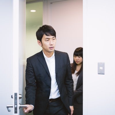 新妙な面持ちで会議室のドアを開けるエリアマネージャーの写真
