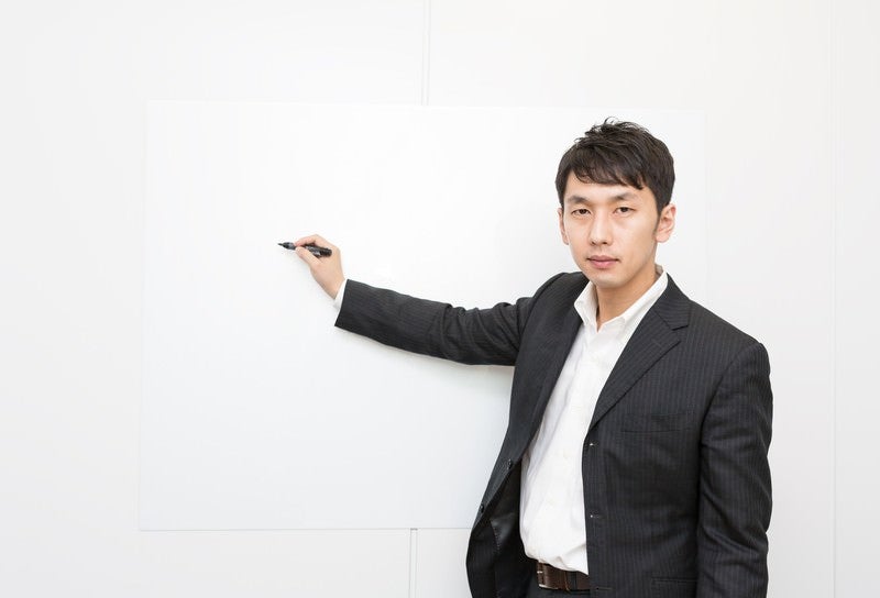 ホワイトボードを使ってプレゼンするホワイト企業の社員の写真