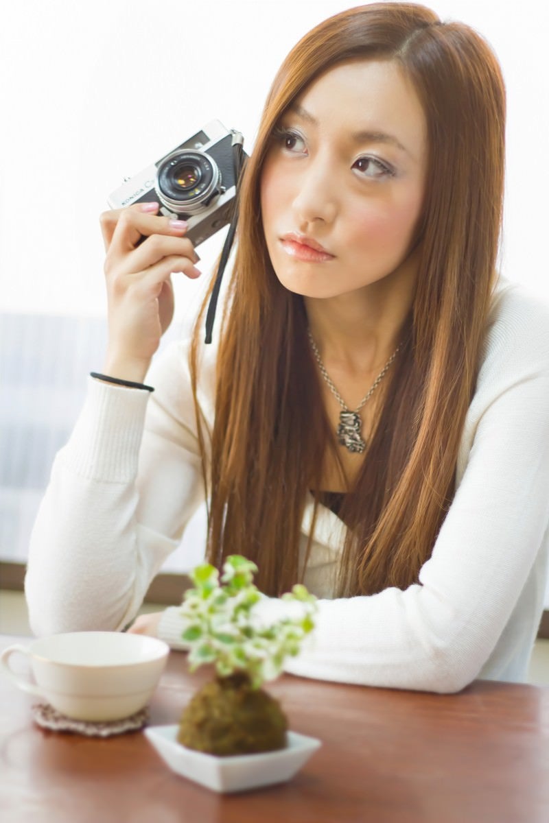レトロなカメラを持って肘をつく女性の写真