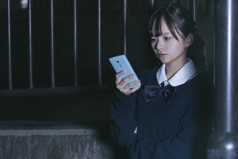 スマホを使って追跡調査する女子高生探偵の写真