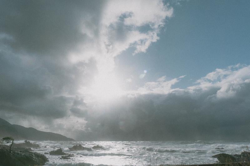 雲の切れ間から届く光に照らされる冬の日本海の写真