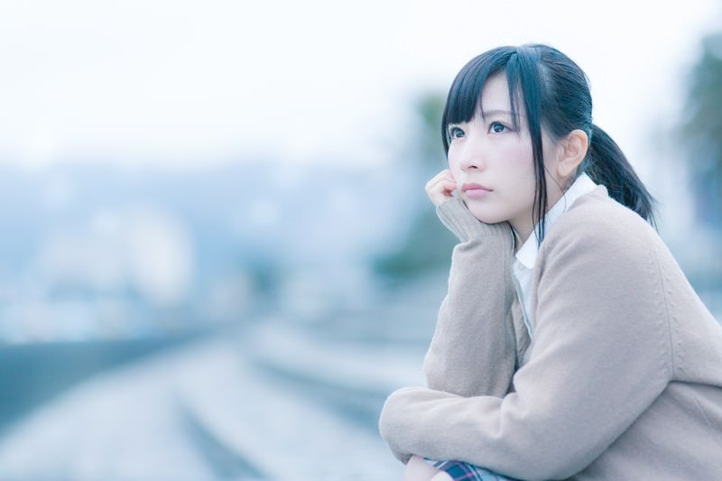 もの寂しげな表情で考えこむ女子高生の写真