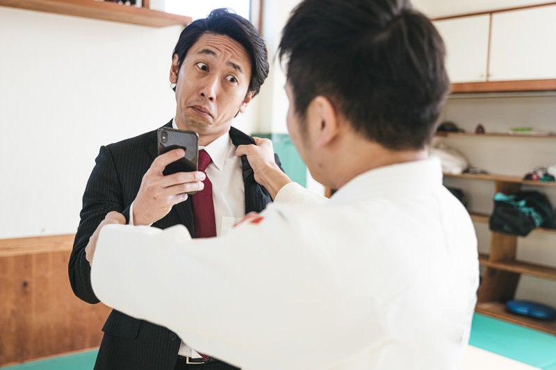 組み手中もスマホを手放さない男性の写真