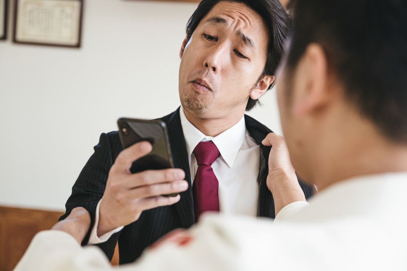 組み手中もメールチェックを欠かさない青年実業家の写真
