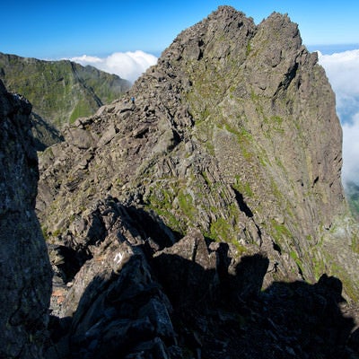 絶壁の岩場を登る登山者の写真