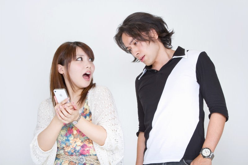 恋人の携帯電話を覗き見する男性の写真
