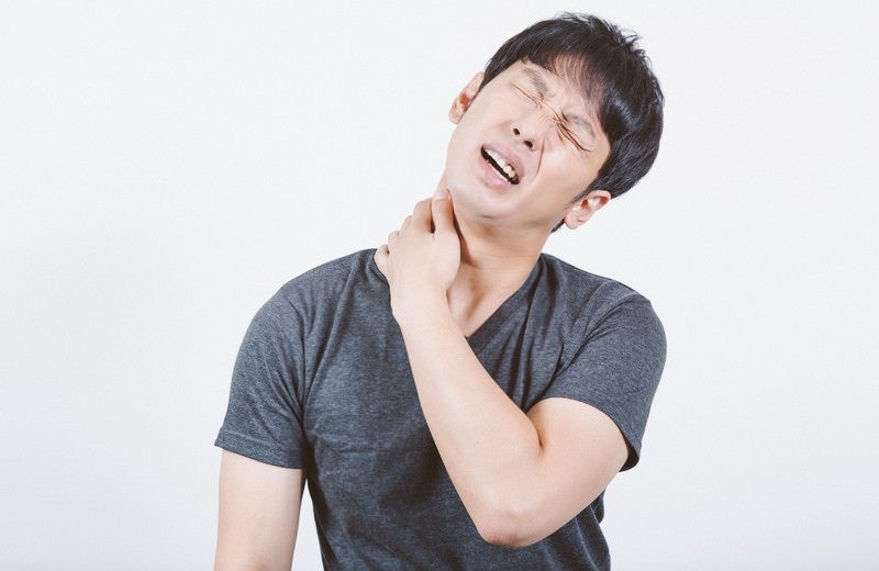 肩こりが酷くて体調が悪い男性の写真