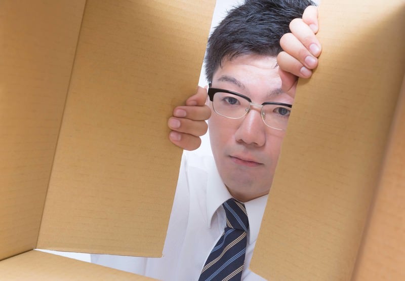 これからダンボールを開けようとする男性の写真
