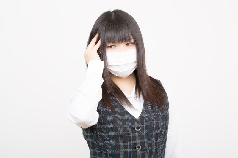 花粉症と頭痛で苦しむOLの写真