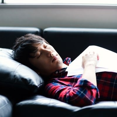 資料を持ちながら寝落ちする男性の写真