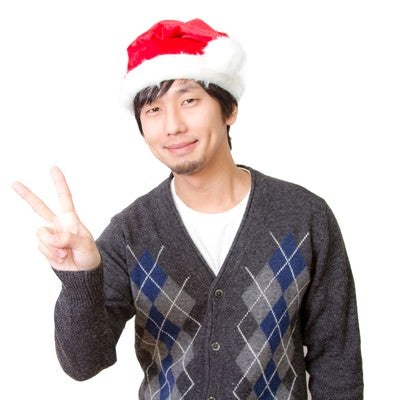 サンタ帽をかぶってピースする男性の写真