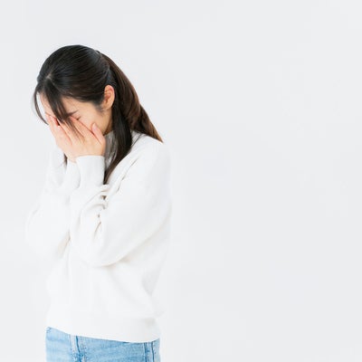 両手で顔を覆う女性の写真