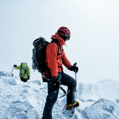 雪山で下山路を見つめる登山者の男性の写真