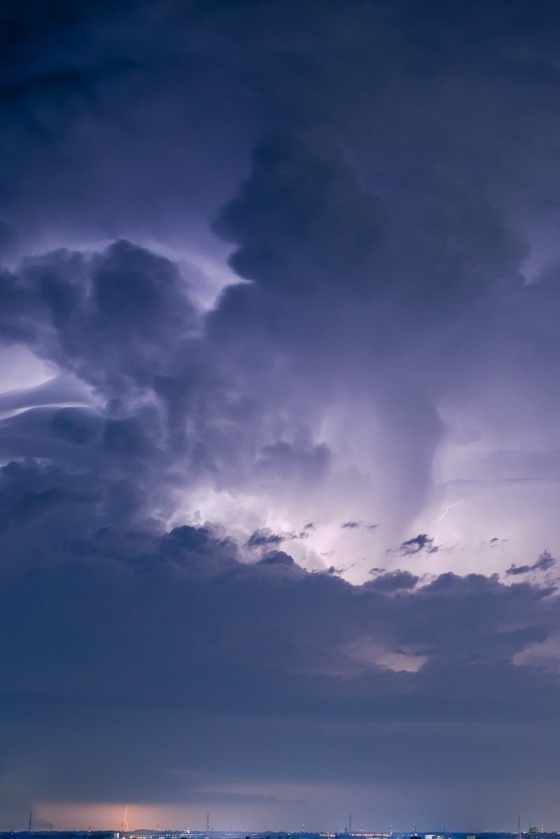 積乱雲と稲妻が街中に落ちる瞬間の写真