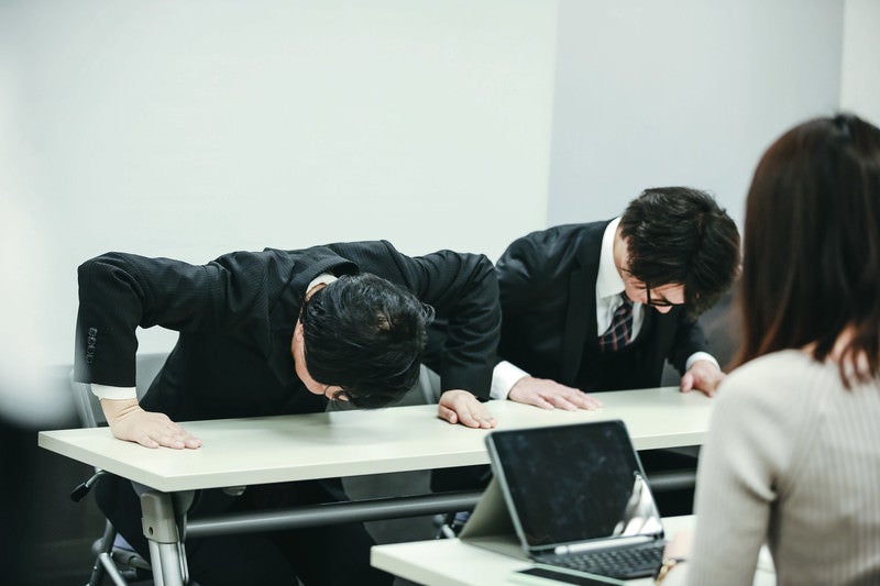 不祥事で謝罪する会社役員の写真