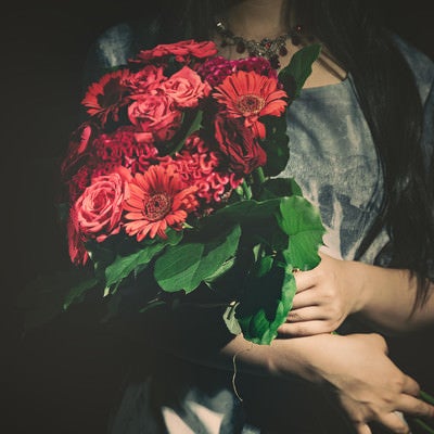 バラの花束をを抱えた女性の写真