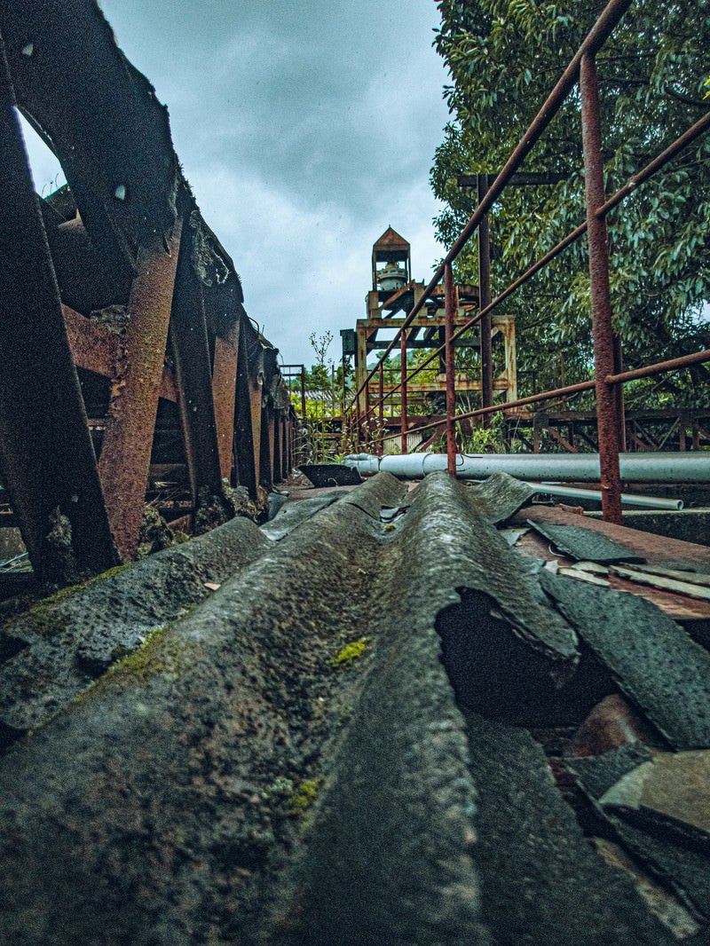 崩れ落ちたトタンと錆び付いた鉄骨の写真