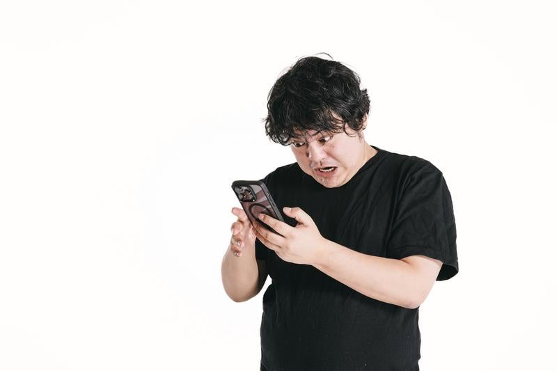 スマホゲームに夢中になる男性の写真