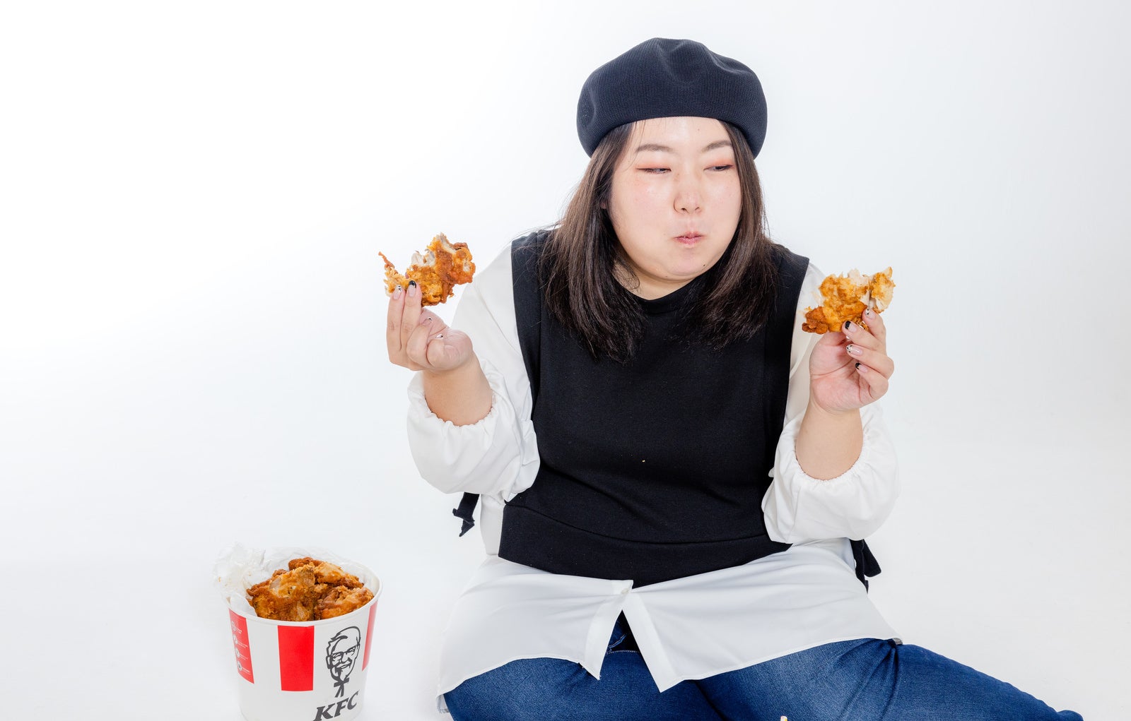 「両手にーフライドチキンを持つ女性」の写真［モデル：KANA］