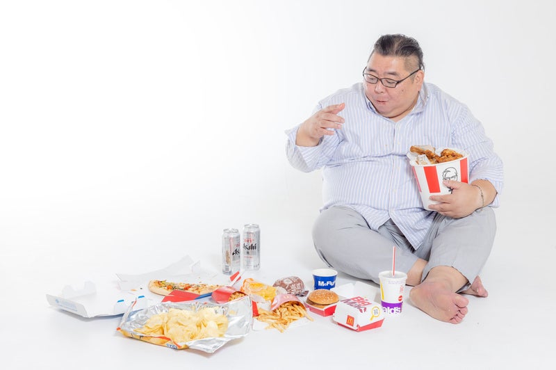 ジャンクフードを物色する暴食中の男性の写真