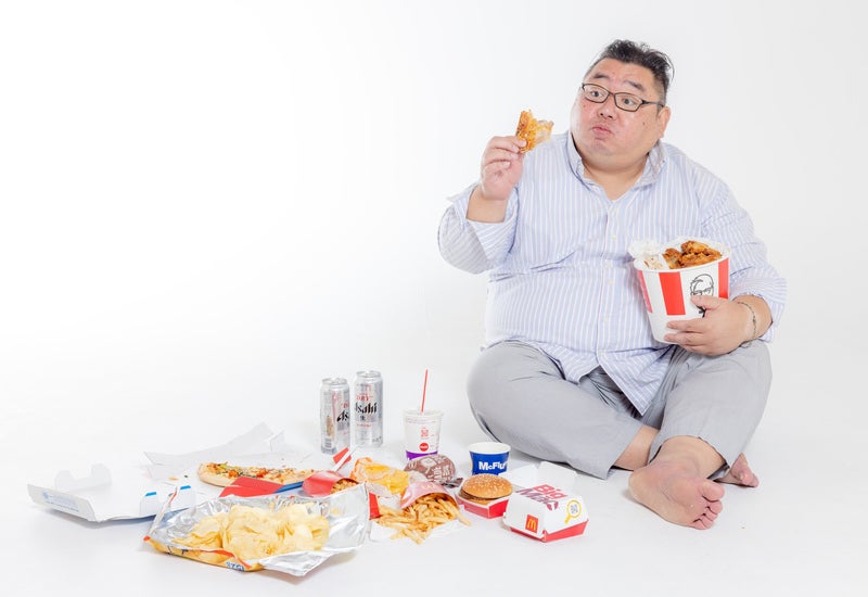ケンタッキーフライドチキンを見つめるジャンクフードに囲まれた男性の写真