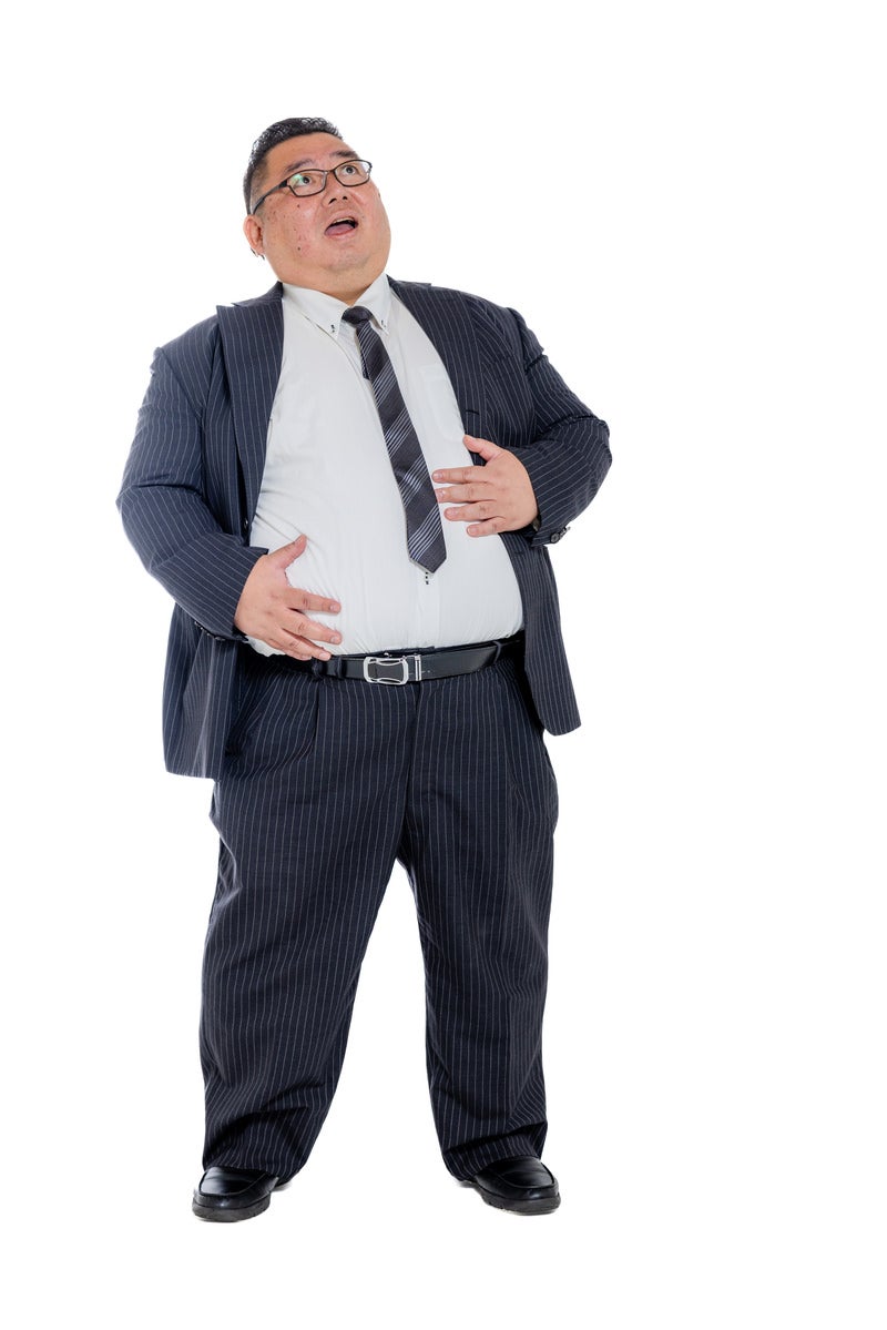 両手でお腹をさするスーツ姿の男性の写真