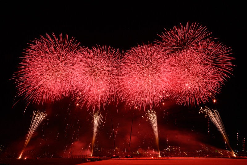 赤い光が夜空を染める江戸川区花火大会のスターマインの写真
