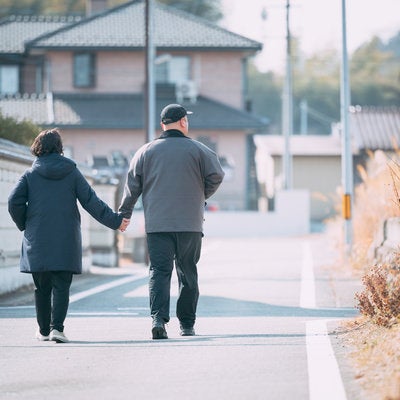 仲良く手を繋いで散歩する夫婦の写真