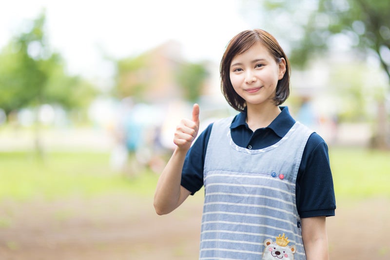 エプロン姿でいいねする女性（屋外）の写真