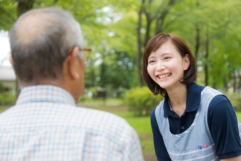 お爺さんの昔話を笑顔で聞く介護士の女性の写真