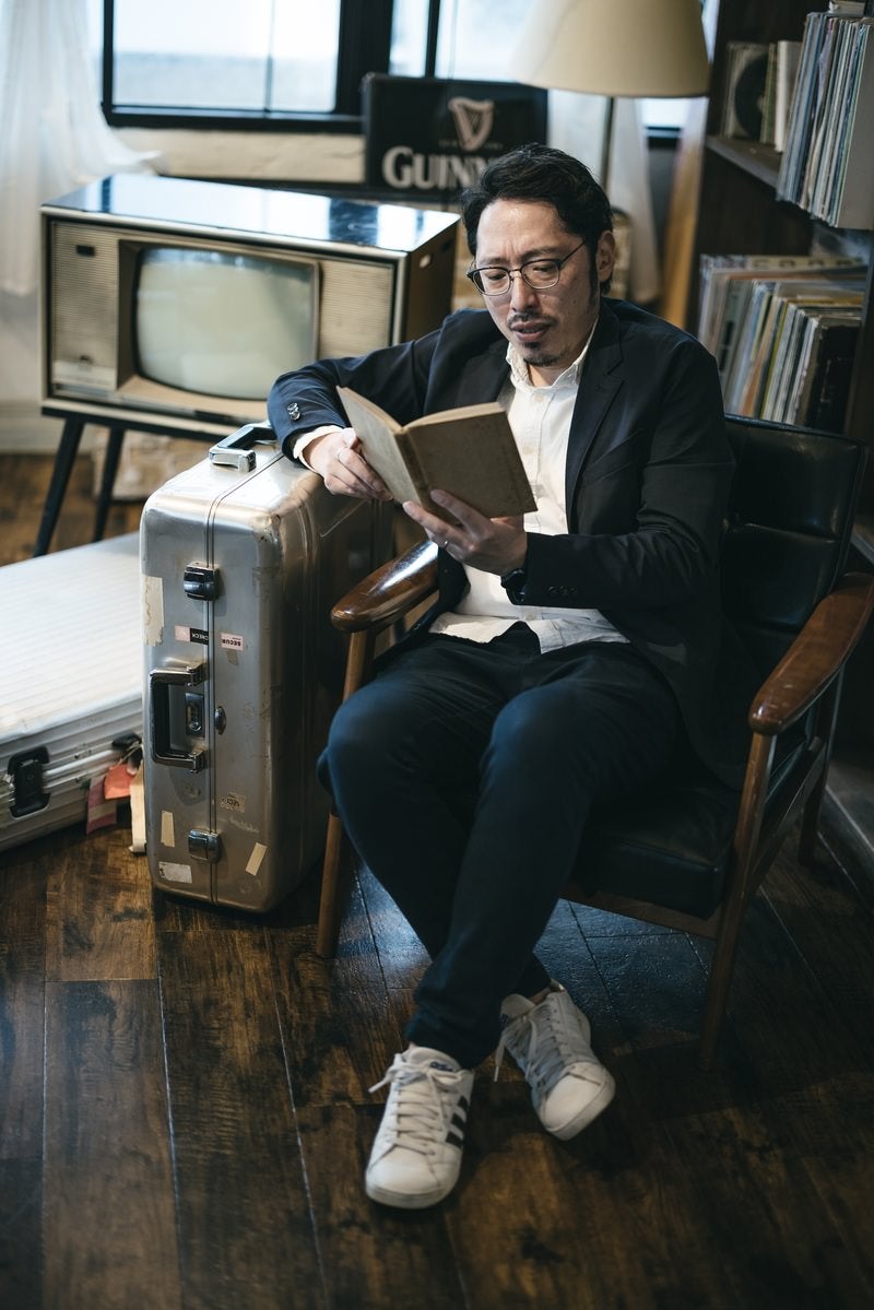 キャリーケースに寄りかかりながら本を読むの写真