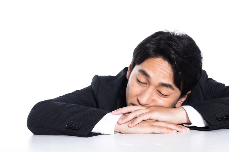 突っ伏して寝る会社員の写真