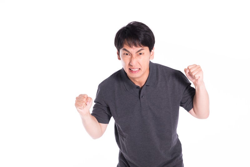 怒りに任せて暴力をふるいそうになるも我慢する男性の写真