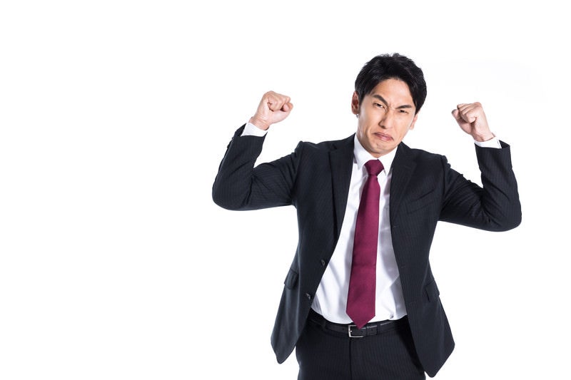 強面で拳を振り上げて悔しがる会社員の写真