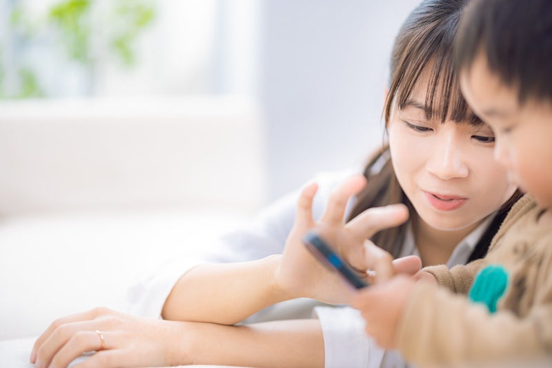 子供とスマホゲームを楽しむママの写真