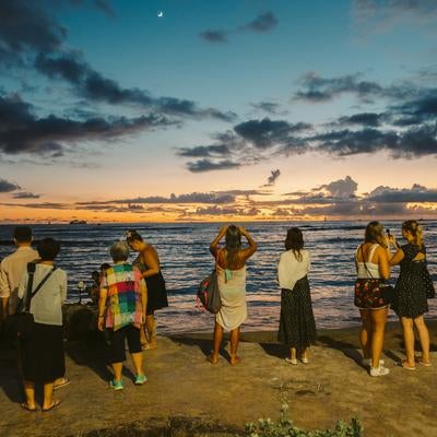 海沿いで日の出に集まる外国人観光客の写真
