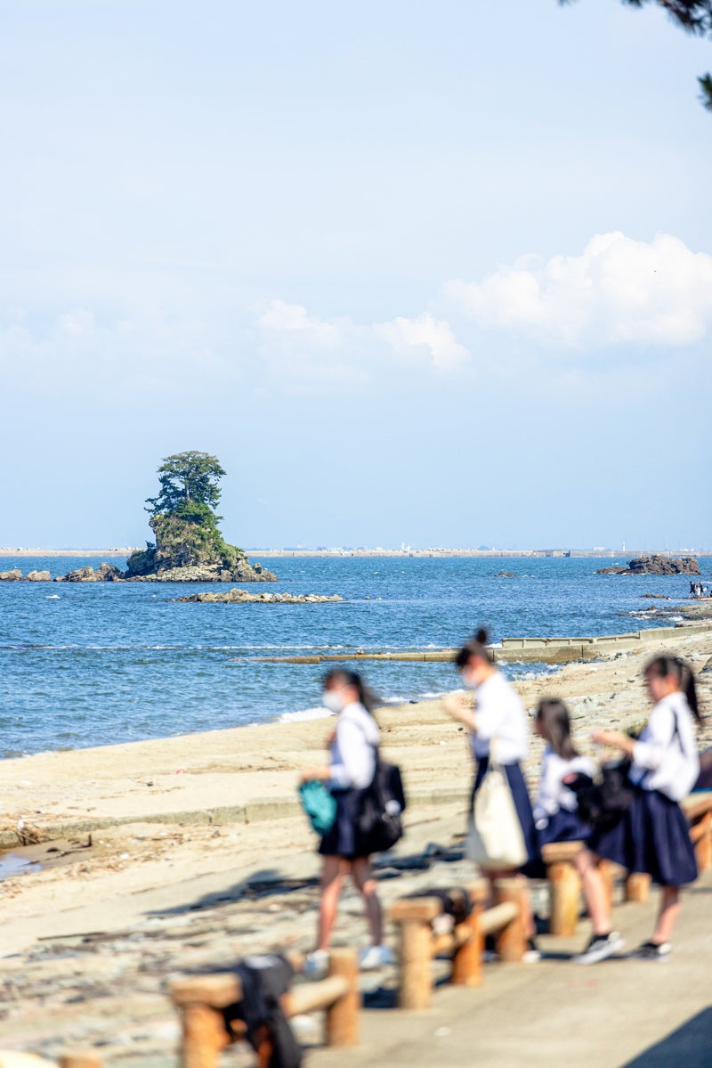 「雨晴海岸の女岩 (めいわ)と女子学生」の写真