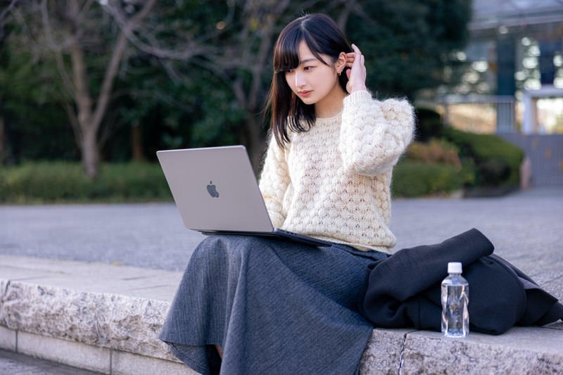 気晴らしに外に出て作業をする女性の写真