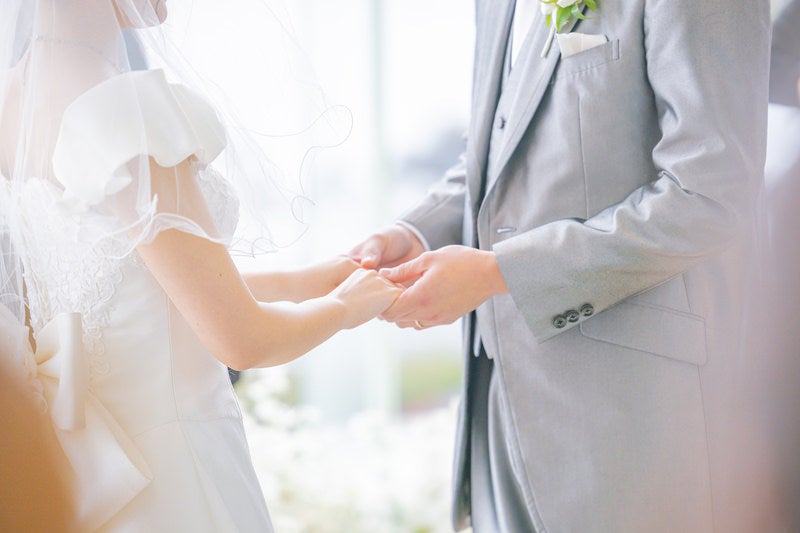 結婚式の指輪交換を終えて花嫁の手をもつ優しい新郎の手元の写真