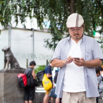 ポケモノミクスに興じるハンチング帽子の男性の写真