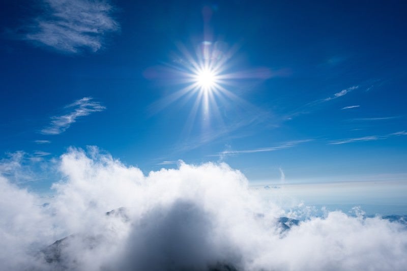 上空の強い日差しと青空の写真