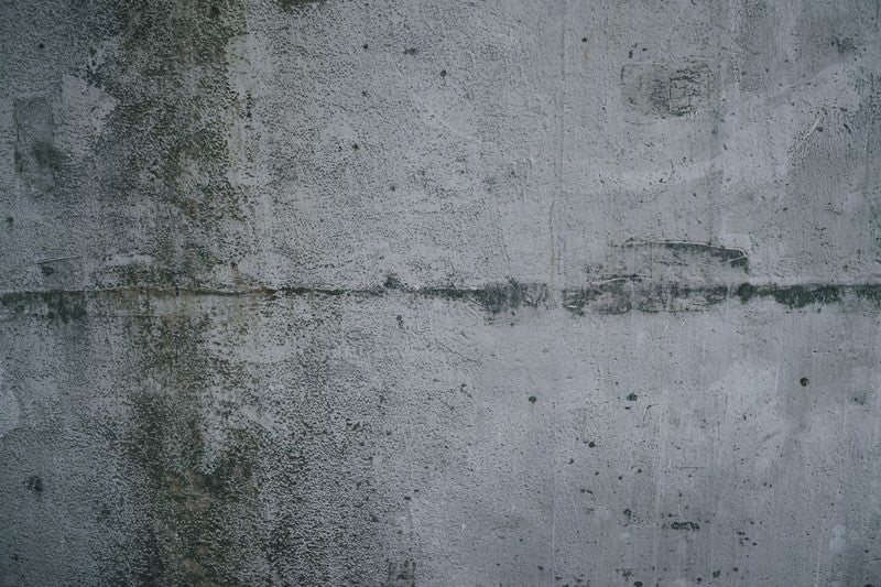 汚れに薄っすらと落書き跡が浮いたコンクリート壁（テクスチャー）の写真